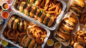 Home 26 Large catering trays from Cook Out with burgers, chicken strips, sides, and sauces