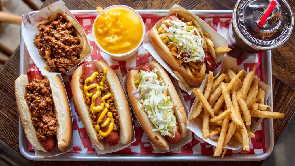 Tray of Cookout hot dogs with chili, cheese, and slaw, served with fries and drink.